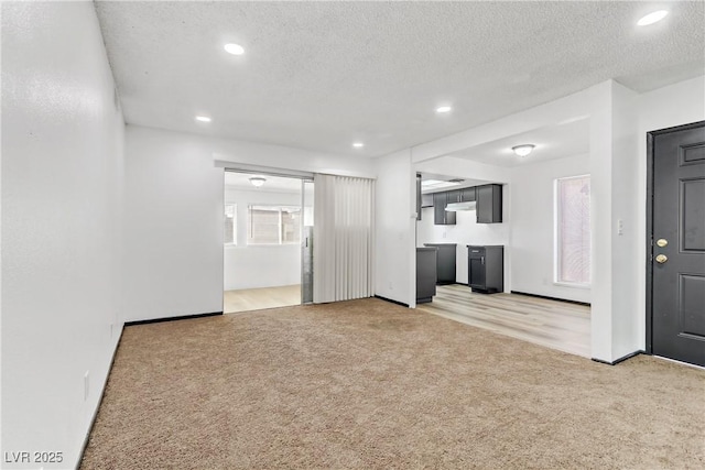 unfurnished living room with recessed lighting, light colored carpet, and a textured ceiling