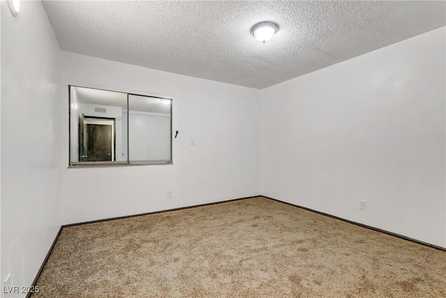 carpeted spare room featuring baseboards and a textured ceiling