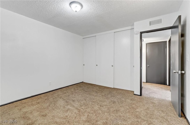 unfurnished bedroom featuring visible vents, a textured ceiling, a closet, and carpet flooring