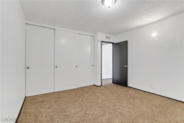 unfurnished bedroom featuring a closet, visible vents, a textured ceiling, and carpet