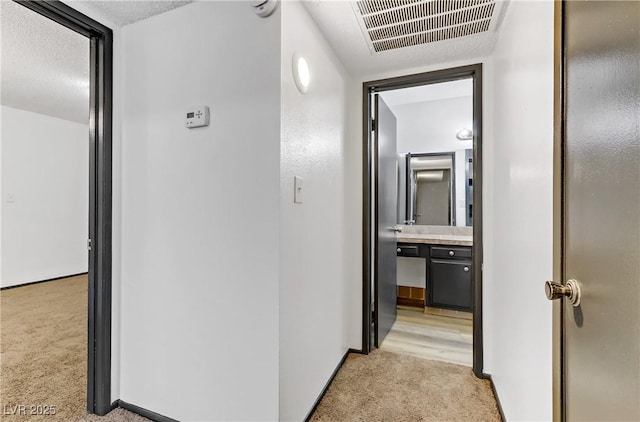 corridor featuring light carpet, visible vents, and baseboards