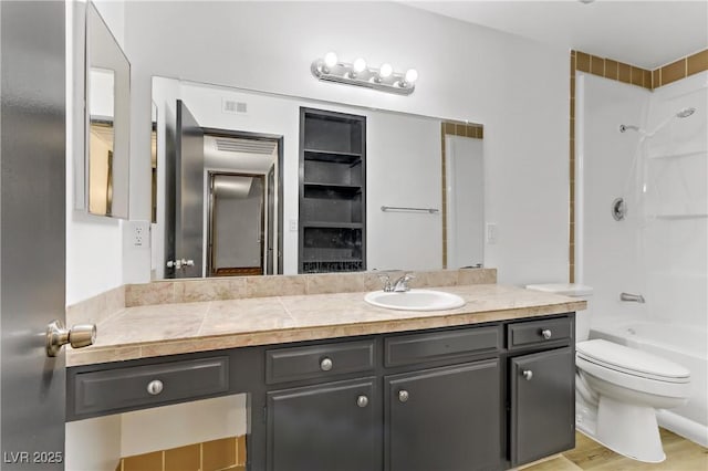 bathroom with visible vents, toilet, wood finished floors, washtub / shower combination, and vanity