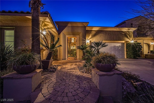 view of front of home featuring an attached garage, driveway, and stucco siding