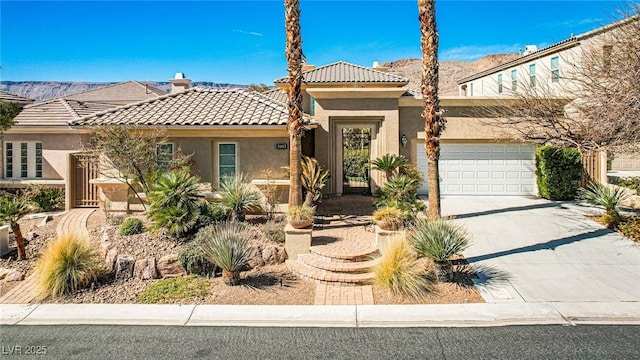 mediterranean / spanish home with a tiled roof, an attached garage, driveway, and stucco siding