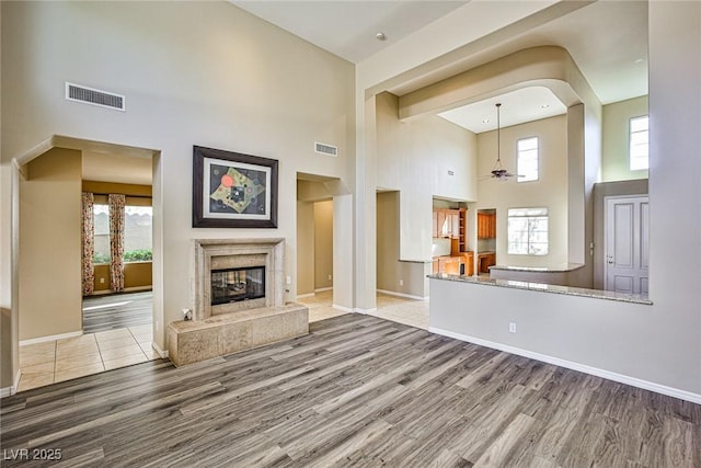 unfurnished living room with visible vents, a fireplace, baseboards, and wood finished floors