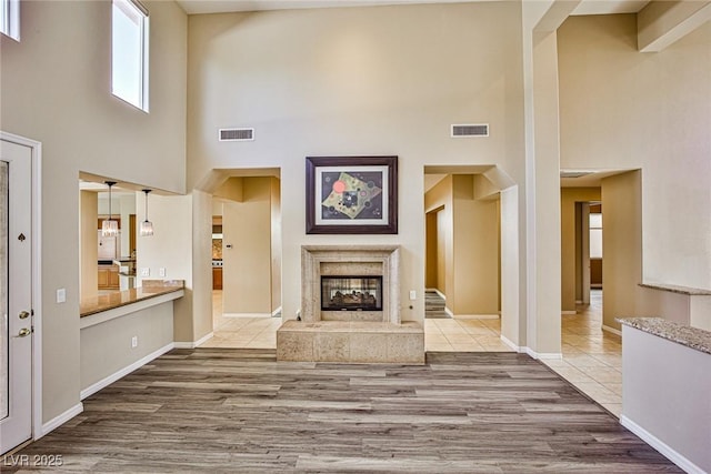 unfurnished living room featuring visible vents, a multi sided fireplace, baseboards, and wood finished floors