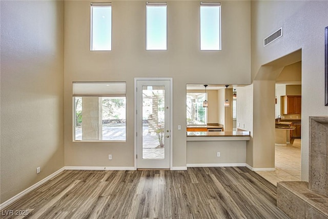 doorway to outside with visible vents, baseboards, a healthy amount of sunlight, and wood finished floors