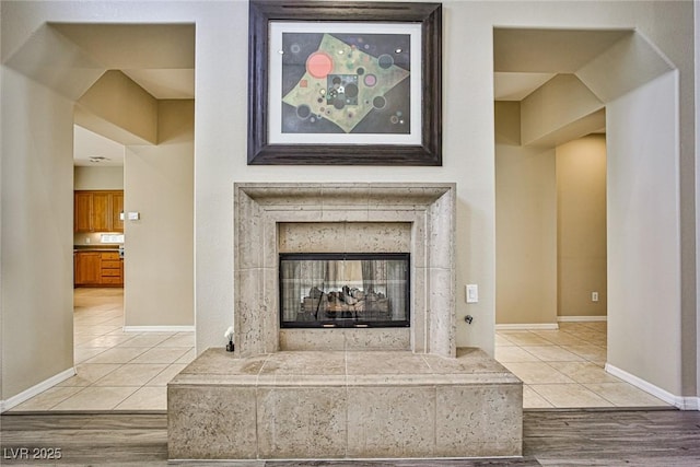 interior details featuring a tiled fireplace, wood finished floors, and baseboards