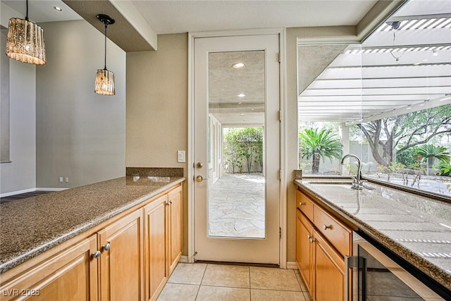 kitchen with beverage cooler, a sink, decorative light fixtures, dark stone counters, and light tile patterned flooring