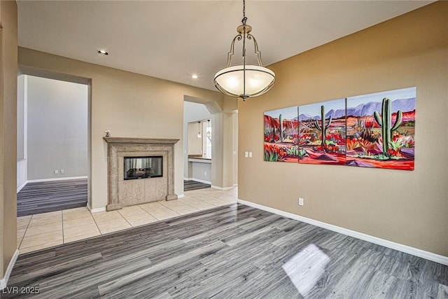 unfurnished living room featuring baseboards, wood finished floors, and a tile fireplace