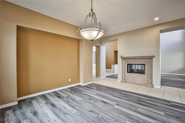 unfurnished living room featuring recessed lighting, baseboards, a multi sided fireplace, and wood finished floors