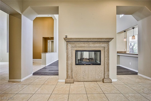 unfurnished living room with tile patterned flooring, a tiled fireplace, and baseboards