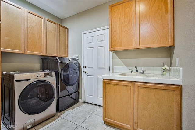 laundry room with washer and clothes dryer, light tile patterned floors, cabinet space, and a sink