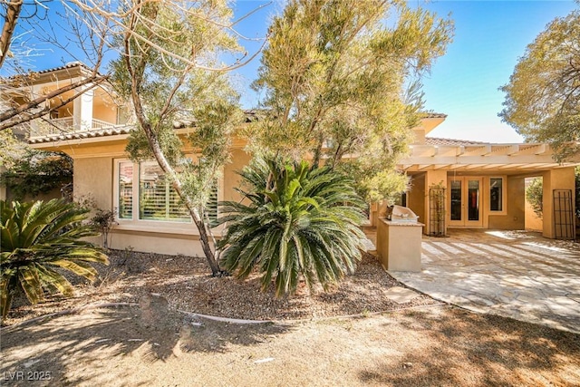 view of side of home with a tile roof and stucco siding