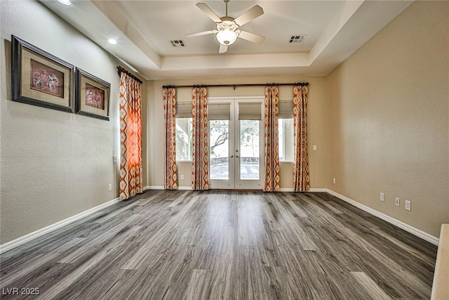 unfurnished room with french doors, baseboards, a tray ceiling, and wood finished floors