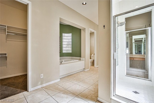 bathroom featuring toilet, a bath, a spacious closet, and tile patterned flooring