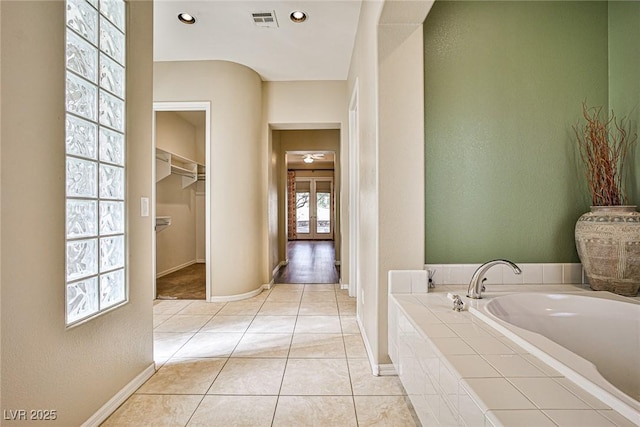 full bathroom featuring tile patterned floors, a garden tub, baseboards, and visible vents