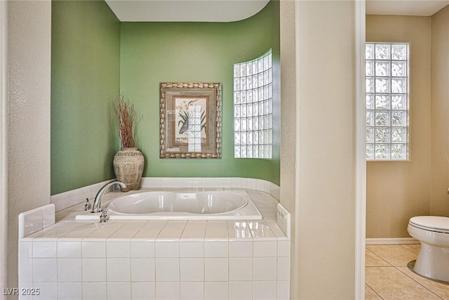 bathroom featuring tile patterned floors, baseboards, toilet, and a garden tub