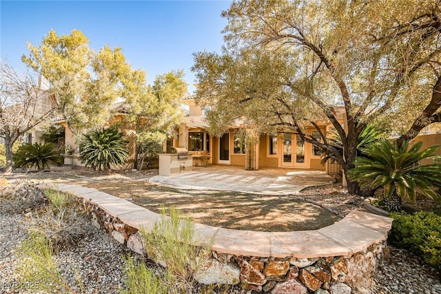 rear view of house with stucco siding, a patio, and area for grilling