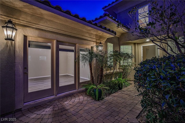 doorway to property featuring stucco siding and a patio