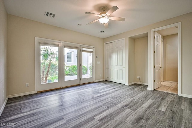 interior space featuring visible vents, baseboards, wood finished floors, and a ceiling fan