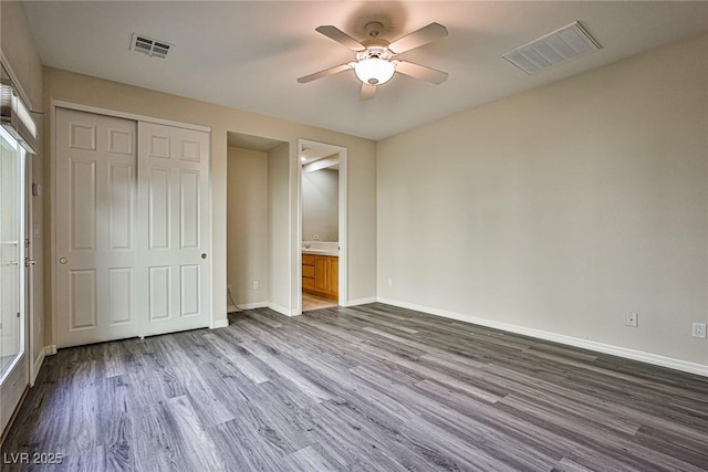 unfurnished bedroom featuring a closet, visible vents, baseboards, and dark wood-style flooring