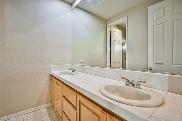 full bathroom featuring double vanity, tile patterned floors, baseboards, and a sink