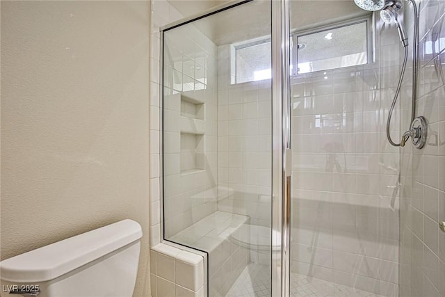 full bathroom with a shower stall, toilet, and a textured wall