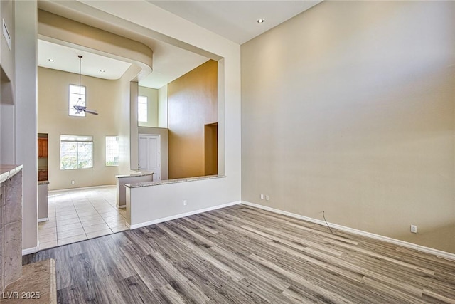 empty room featuring baseboards, wood finished floors, and a towering ceiling