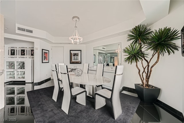 dining space featuring visible vents, a raised ceiling, baseboards, and a chandelier