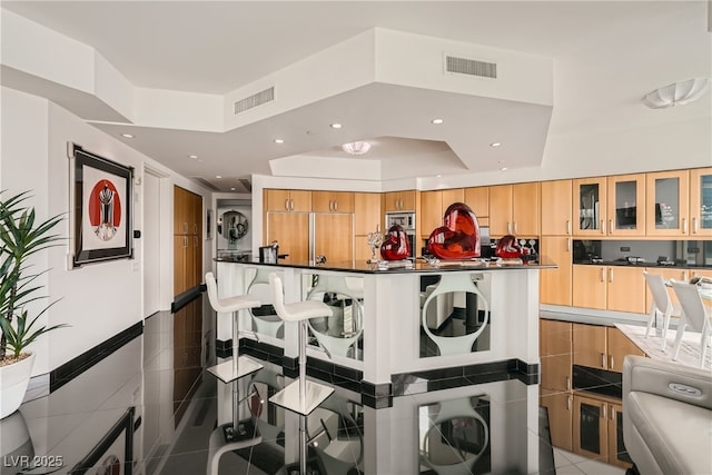 interior space with dark countertops, tile patterned floors, visible vents, and built in appliances