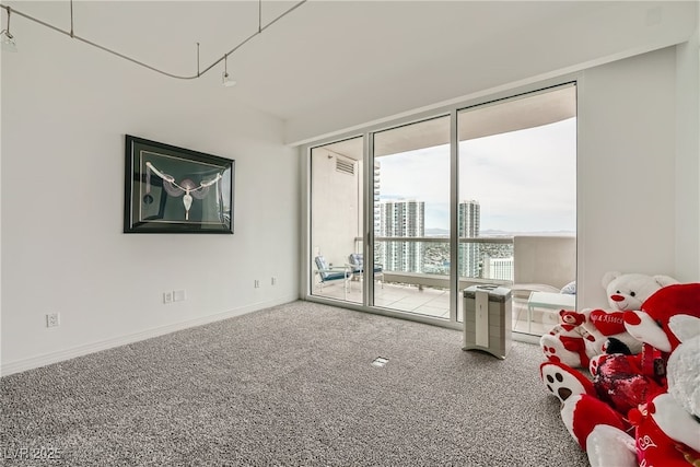 carpeted empty room featuring a city view and baseboards