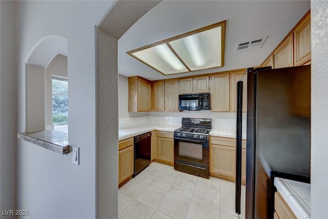 kitchen with visible vents, black appliances, light brown cabinets, tile countertops, and light tile patterned flooring