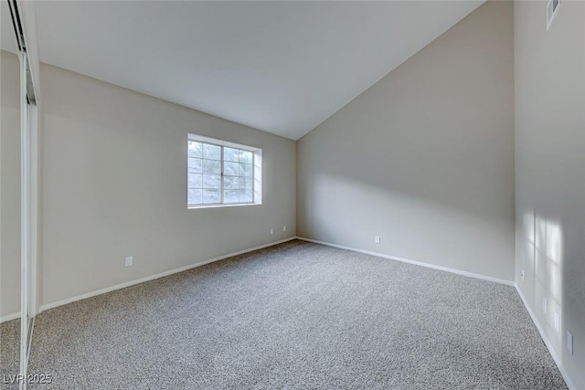 carpeted empty room with baseboards and vaulted ceiling