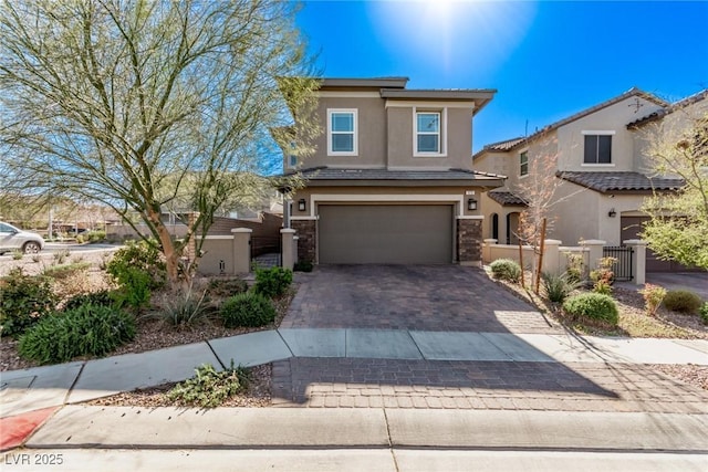 view of front of property featuring stucco siding, decorative driveway, stone siding, fence, and an attached garage