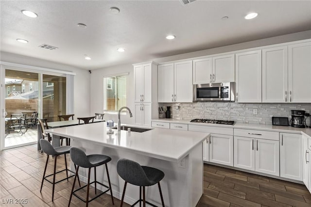 kitchen with stainless steel microwave, a breakfast bar area, light countertops, and decorative backsplash