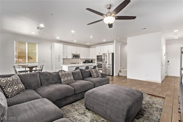 living area featuring visible vents, recessed lighting, stairs, and wood finished floors