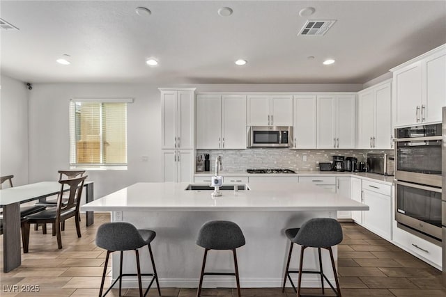 kitchen featuring decorative backsplash, a breakfast bar area, stainless steel appliances, and a sink