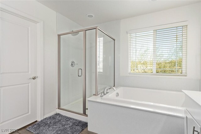 bathroom with a garden tub, a healthy amount of sunlight, and a stall shower