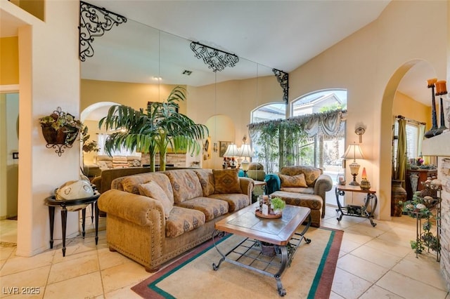 living room featuring tile patterned floors, visible vents, arched walkways, and high vaulted ceiling