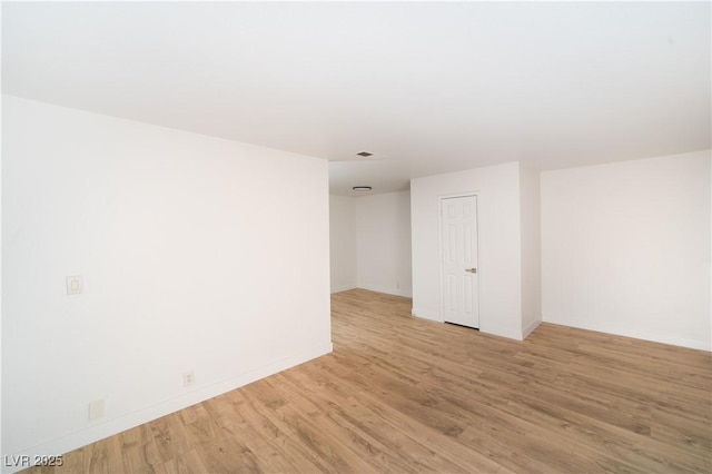 empty room featuring visible vents, light wood-style floors, and baseboards