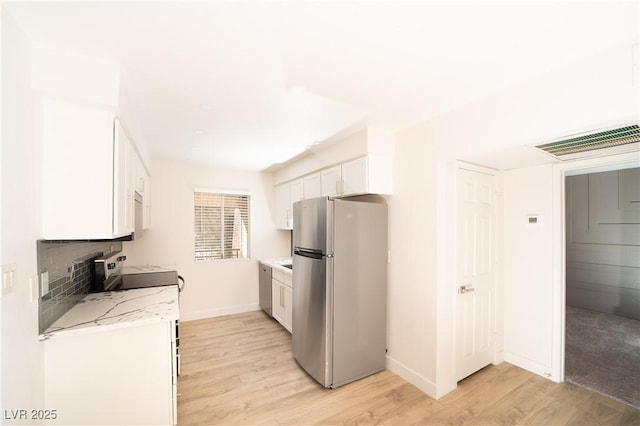 kitchen featuring light wood-style flooring, visible vents, white cabinets, and freestanding refrigerator