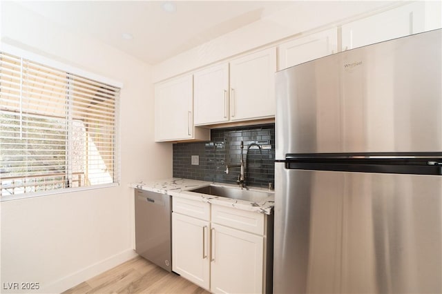 kitchen featuring a sink, stainless steel appliances, tasteful backsplash, and white cabinetry