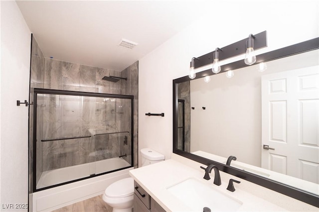 full bath featuring visible vents, toilet, vanity, and shower / bath combination with glass door