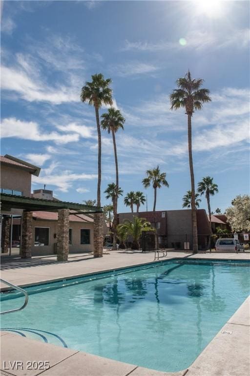 community pool with a patio and fence