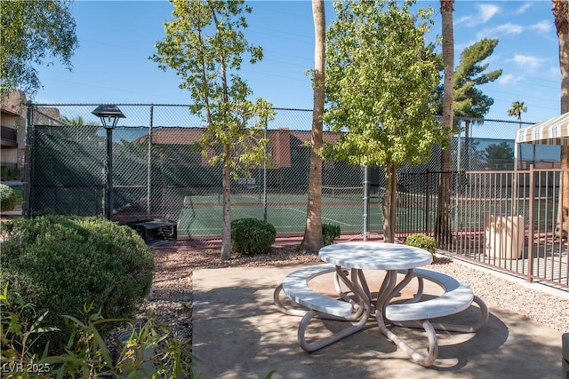 exterior space with a tennis court and fence