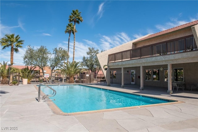 community pool with a patio area and fence