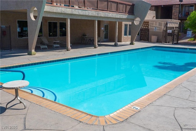 community pool with a patio area and fence