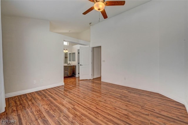 unfurnished room with ceiling fan, high vaulted ceiling, baseboards, and wood finished floors