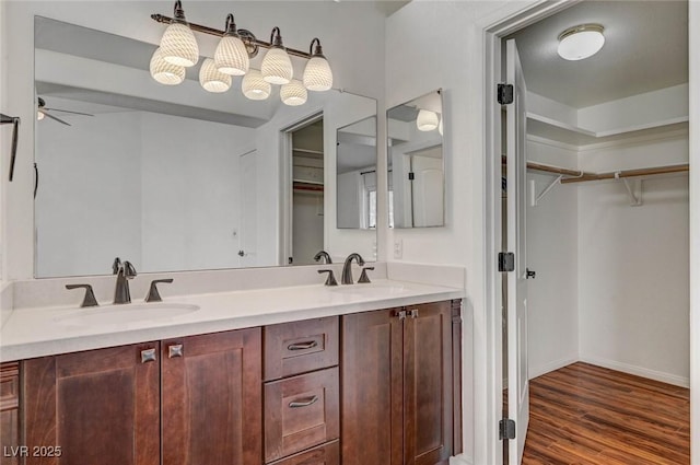 bathroom featuring double vanity, a spacious closet, wood finished floors, and a sink